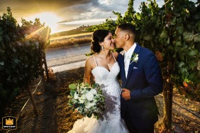 At Garré Vineyard in Livermore, California, the bride and groom stand nose to nose, smiling at each other for a wedding portrait at sunset, lit by the photographer’s flash against the vineyard backdrop.